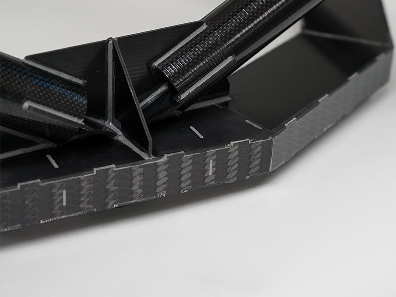 Image shows the completed precision fixture on a white surface and background. The detail image shows a connection juncture. Two carbon fiber tubes are bonded to a carbon sandwich panel structure. The edges of the sandwich panel are covered by carbon fiber paneling.